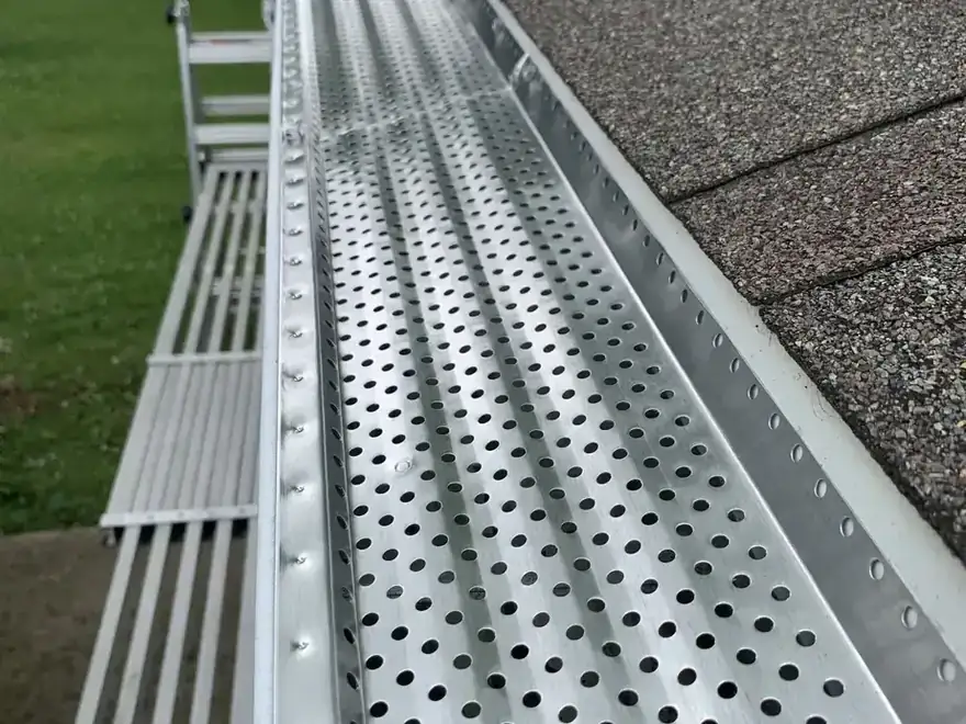 Perforated aluminum gutter guard fitted over a gutter, close up