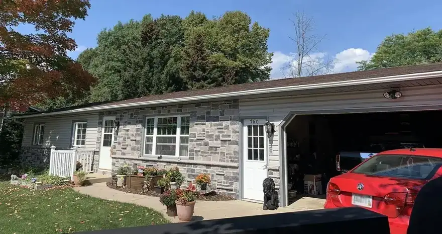Stone and siding ranch house with gutters along the full roofline