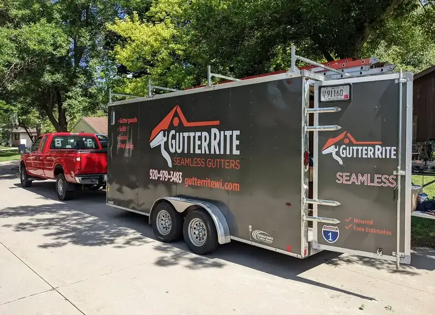 The Gutter Rite charcoal work trailer, lettered with the company name, hitched to a red pickup on a residential street